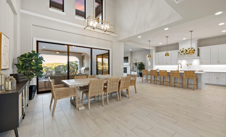 Enter directly into your two-story dining area, bathed in natural light pouring through a glass slider door. A striking contemporary light fixture adds a touch of elegance to the ambiance.