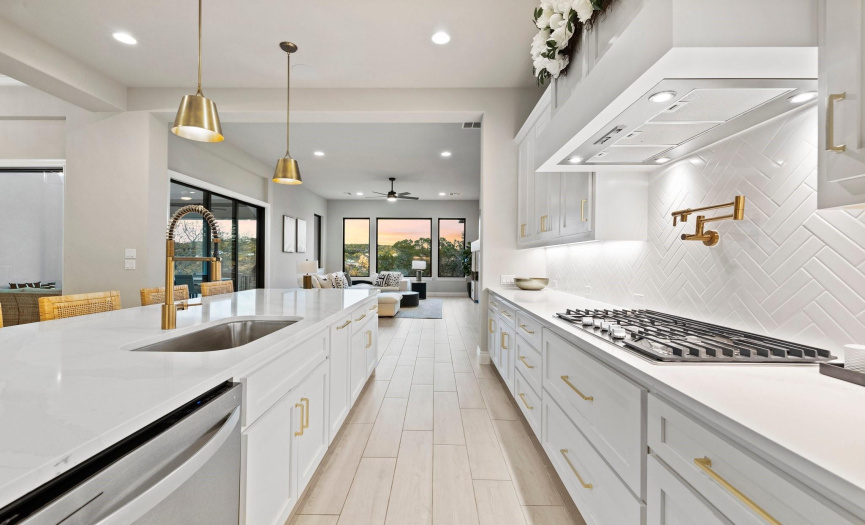The exceptional chef's kitchen is a work of art, boasting quartz countertops, a white herringbone-style backsplash, and shaker-style cabinetry accentuated with brass hardware. 