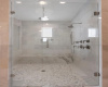 Marble shower with bench seating and multiple shower heads 