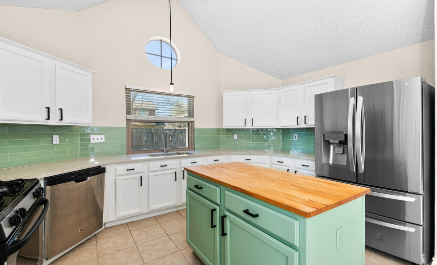 Large island with butcher block countertop playfully echoes the sea glass green backsplash.