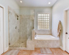 En-suite of the primary features extra large step in shower with a seat and a grand soaking tub