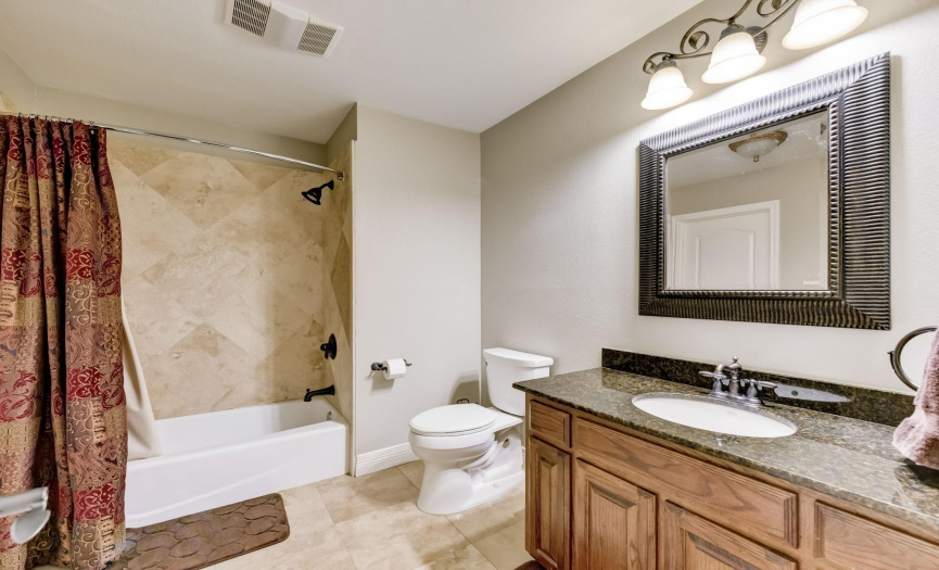 Secondary bathroom features tile wall and granite countertop