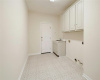 Lengthy laundry room with overhead cabinets and wash basin