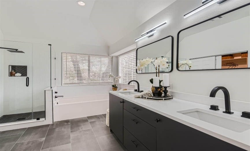 Remodeled primary bath with new cabinets with double vanities, quartz counters, undermount sinks, updated hardware, faucets, mirrors and lighting