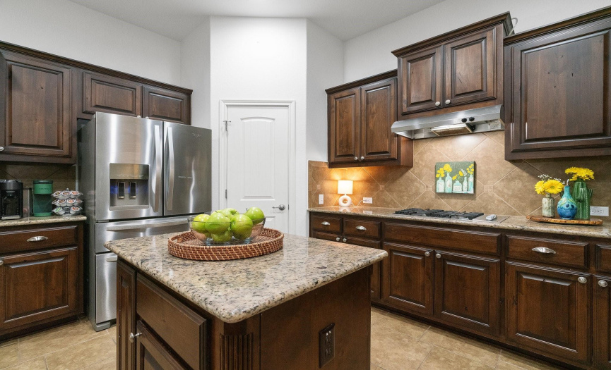 Featuring sleek stainless steel appliances (built-in oven & microwave, gas cooktop, and dishwasher), granite countertops, a pantry, a convenient center prep island, and lovely tile backsplash.
