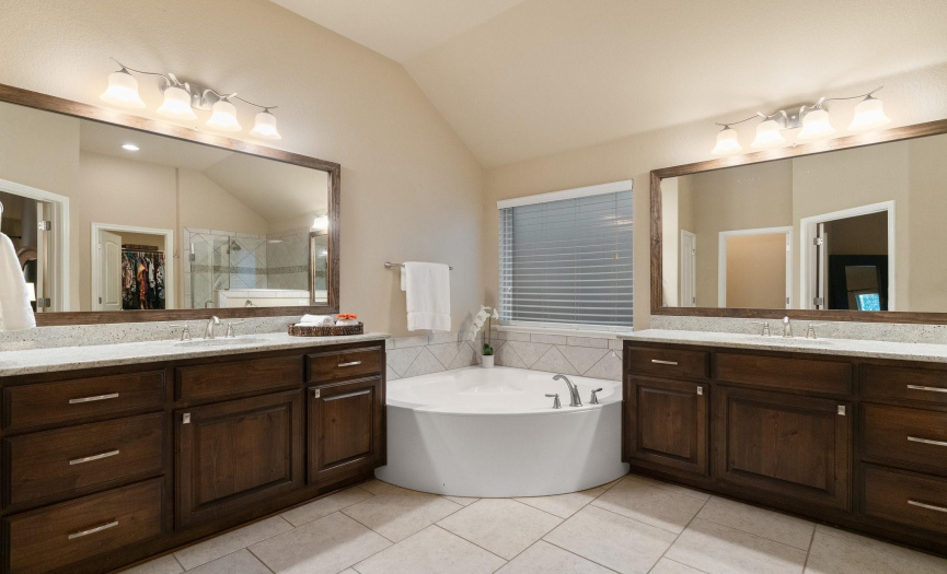 Double doors off the primary suite open into this gorgeous private ensuite bathroom with separate, sizable dual vanities and beautifully stained cabinetry. 