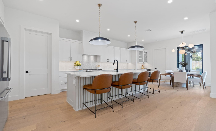 Sun-drenched gourmet kitchen featuring top-tier appliances, custom cabinetry, and a generously sized island, perfect for hosting gatherings and culinary adventures.