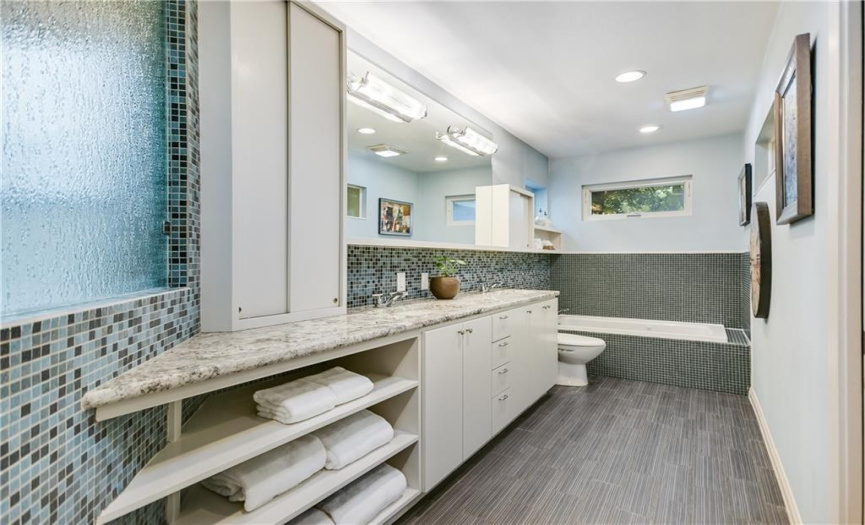 Indulge in luxury in the primary bathroom adorned with floor-to-ceiling tile, offering a serene oasis for relaxation and rejuvenation.
