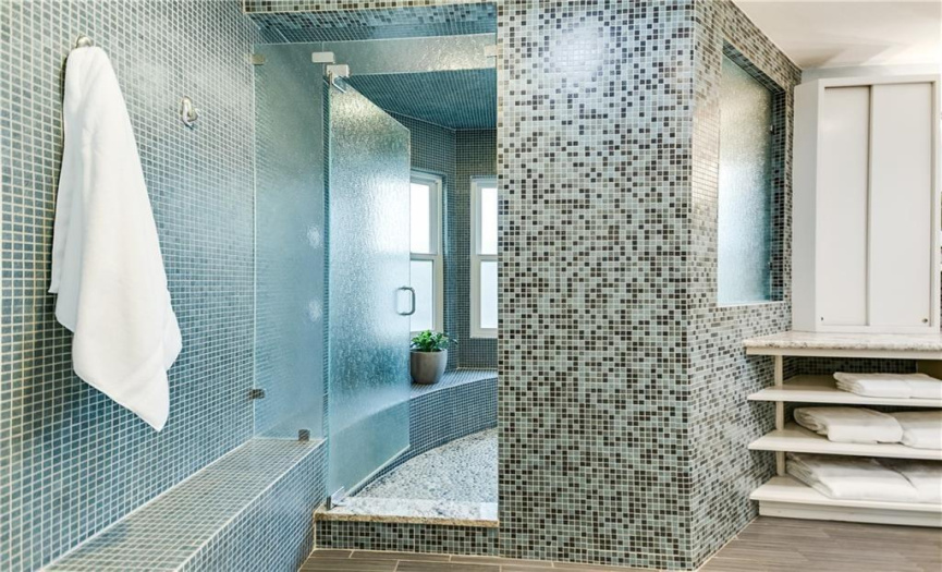 Unwind in the massive walk-in shower featuring a bench seat, providing ample space for a spa-like experience right at home.