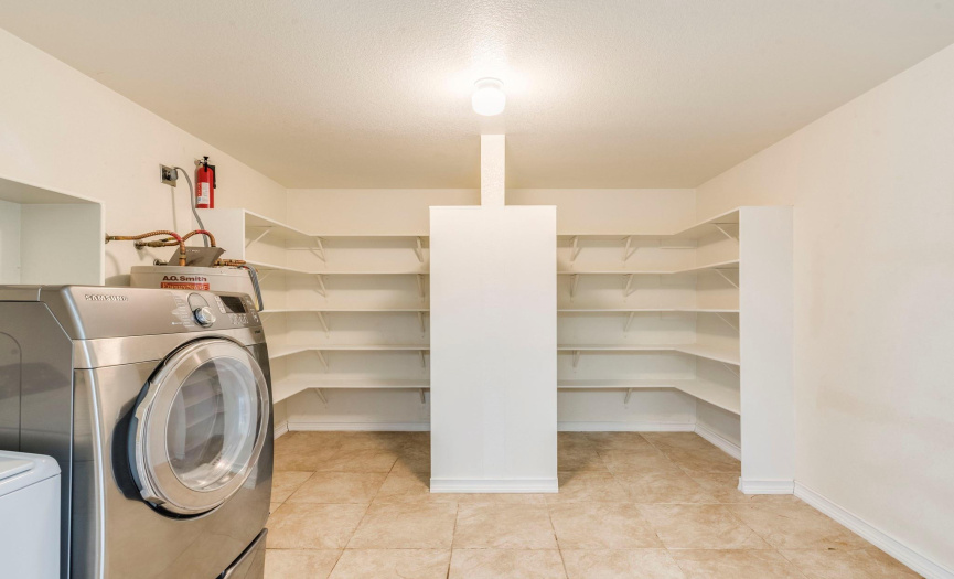 Functional utility room with modern washer, ample shelving, and tiled flooring—perfect for laundry, pantry, and additional storage needs.