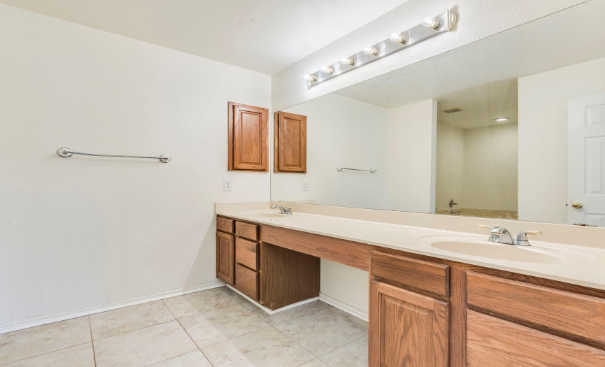 Spacious primary bath with large vanity, ample storage, and deep soaking tub for a relaxing at-home spa experience.