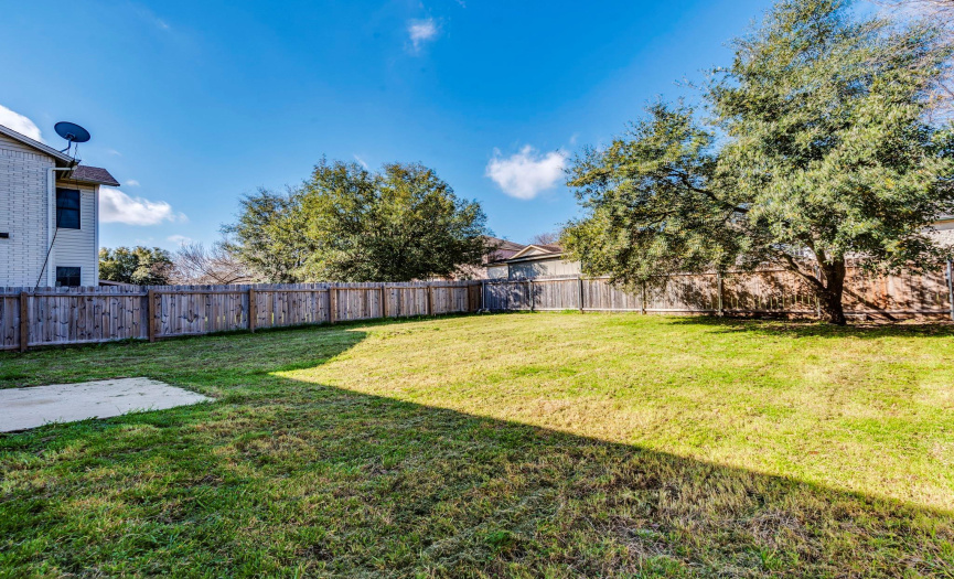 Spacious and private fenced backyard with lush lawn and mature trees—perfect for outdoor activities and personal landscaping projects.