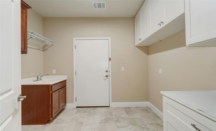 Laundry room with ample cabinets and a useful wash basin.