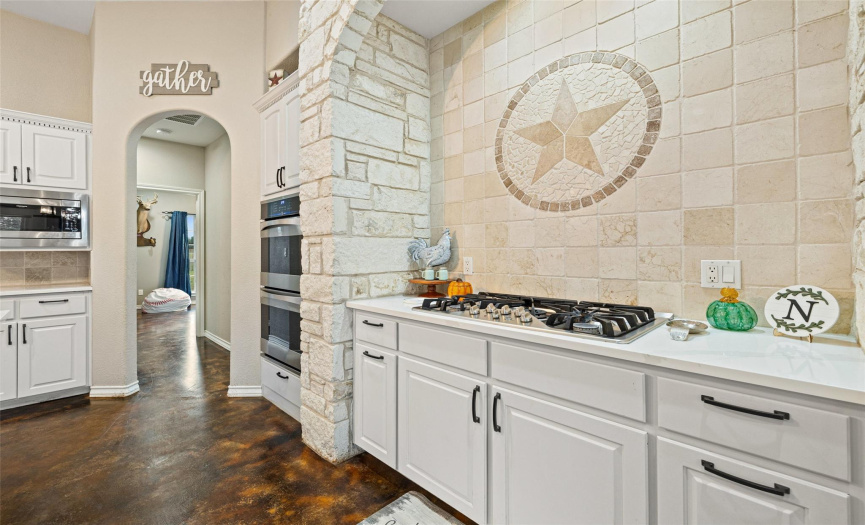 The focal centerpiece in the kitchen is the stunning custom stone archway framing the gas cooktop and the intricate tile backsplash honoring the home's Texas heritage. 