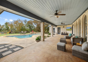 The backyard entertainer's oasis comes complete with a huge covered back porch with overhead fans, wood wrapped ceiling, stone pillars, and plenty of space for outdoor living and dining. 