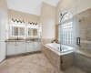 Bright, spacious primary bathroom with dual vanity and  large soaker tub and step-in glass shower
