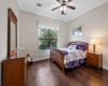 Comfortable guest bedroom with hardwood floors and large window.