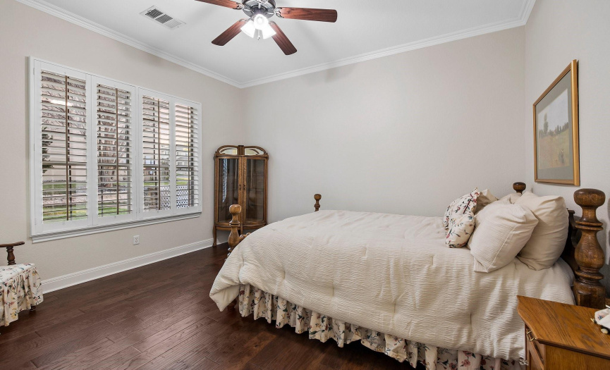 Serene guest bedroom with elegant shutters and rich wood flooring