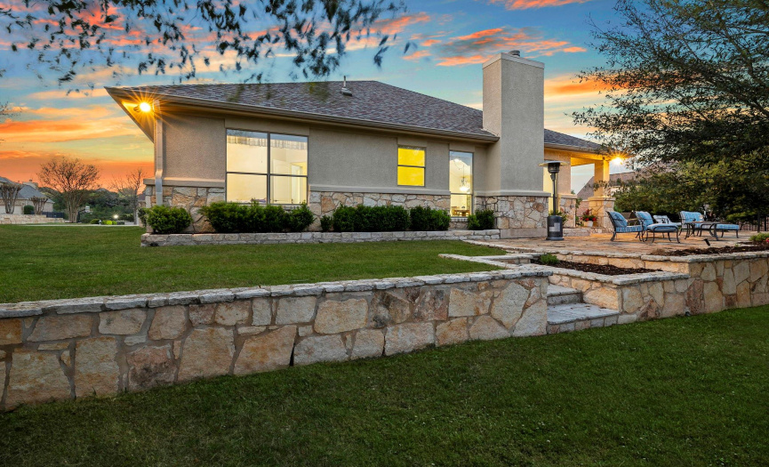 Expansive backyard with stone patio, ideal for leisure and entertainment against a stunning sunset backdrop