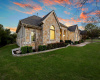 Curb appeal galore with warm windows glowing against a colorful sunset, easy to maintain beds and mature landscaping.