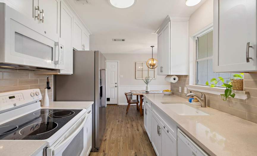 The galley-style kitchen is adorned with white shaker cabinets and quartz counters.
