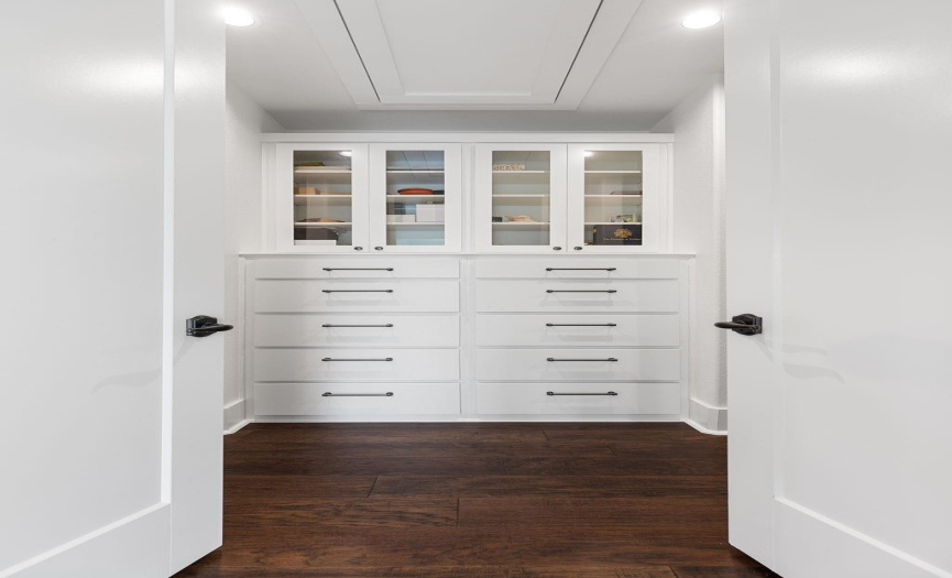 Large walk-in closet with dressing area with built-in drawers and cabinets.