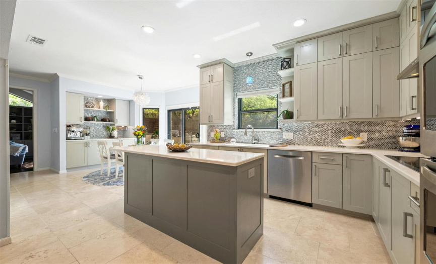 Shaker cabinetry, a tile backsplash, quartz countertops, and high-end stainless steel appliances, including an electric cooktop and double ovens, make cooking, serving, and entertaining an absolute pleasure