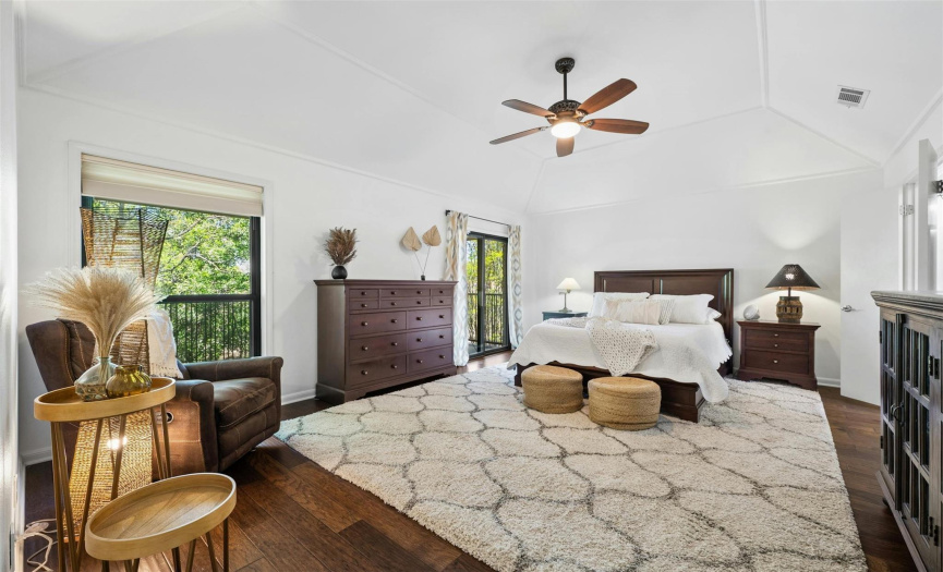 The large primary suite stands out with high ceilings, and a sliding door leading to the front balcony, offering views of the surrounding trees and canyon