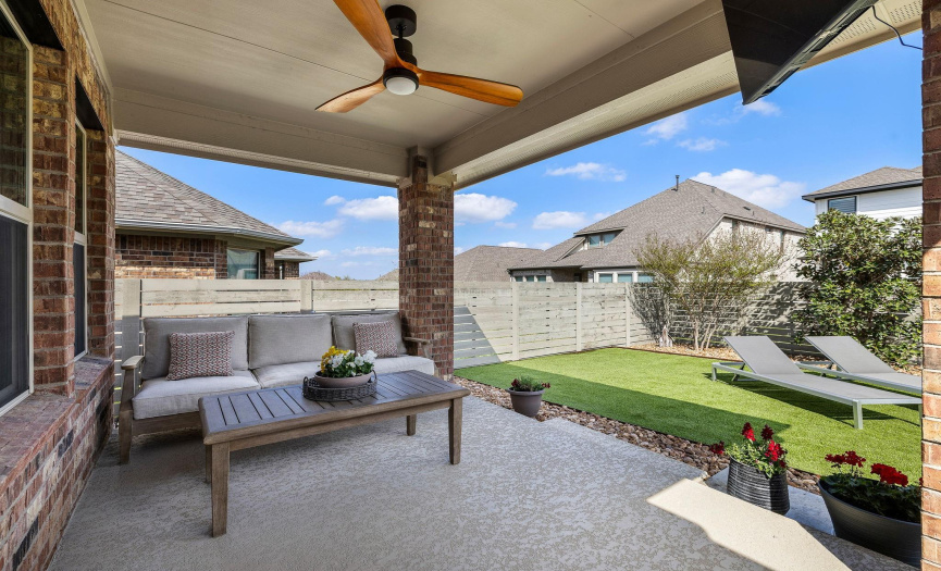 Perfect sized, low maintenance backyard with a covered patio, cooldeck, turf and an in-ground pool.