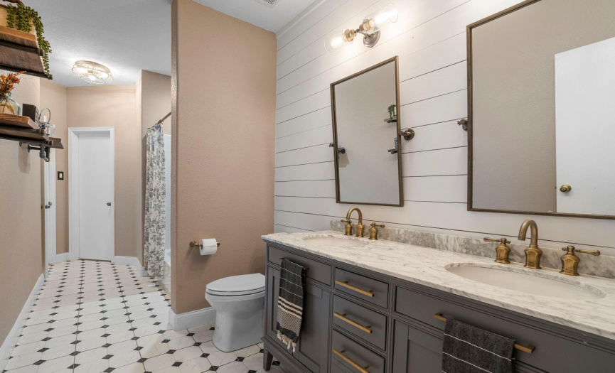 This guest bath oozes charm! Delightful tile floors, a shiplap wall and beautiful double vanity with specialty mirrors.