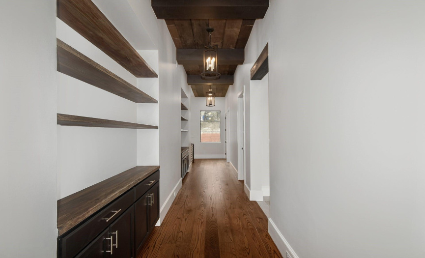 walkway to primary suite with natural wood ceilings and floors 