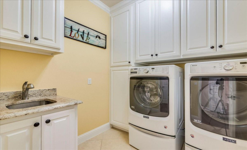 Laundry room with additional cabinetry, sink and washer and dryer convey. 