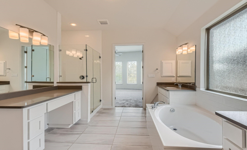 A separate tub and shower and dual vanities grace the spa-like primary bathroom.