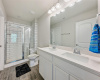 Primary bathroom features dual sinks, modern lighting, wood plank tile flooring and a beautiful walk in shower with white subway tile and charcoal grout.