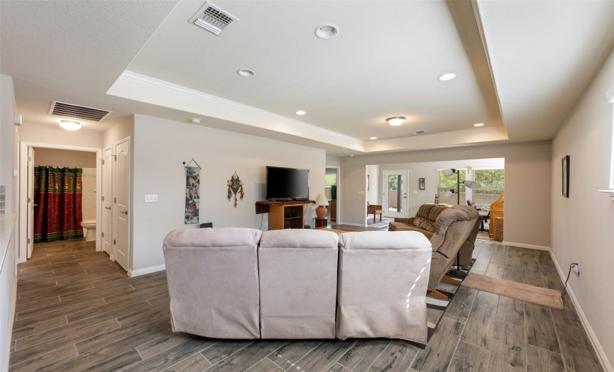 Large living room features wood plank tile flooring and a tray ceiling.