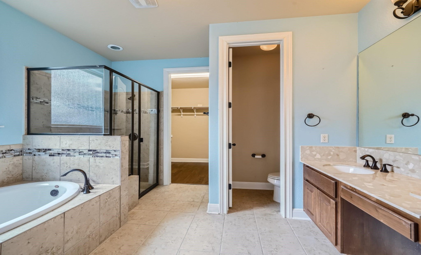 Primary bathroom also features a separate shower and garden tub. Sizeable walk-in closet is just beyond.