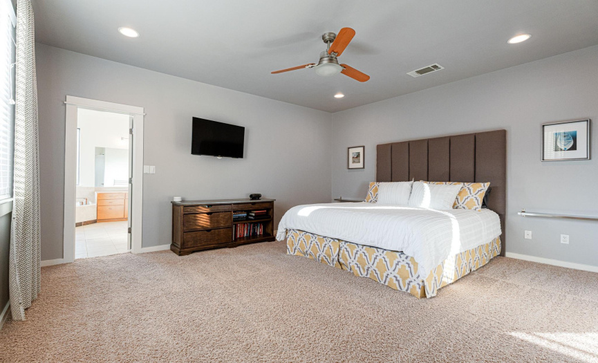 Oversized primary bedroom features large window, recessed lighting, ceiling fan and ensuite.