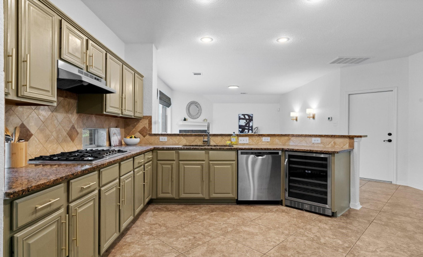  Stainless steel appliances, including a sleek gas cooktop and convenient wine fridge, elevate the culinary experience in this modern kitchen.