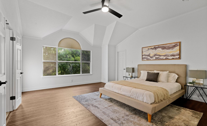 Retreat to the primary bedroom sanctuary, boasting hardwood flooring, a vaulted ceiling, and ample natural light for a cozy atmosphere.