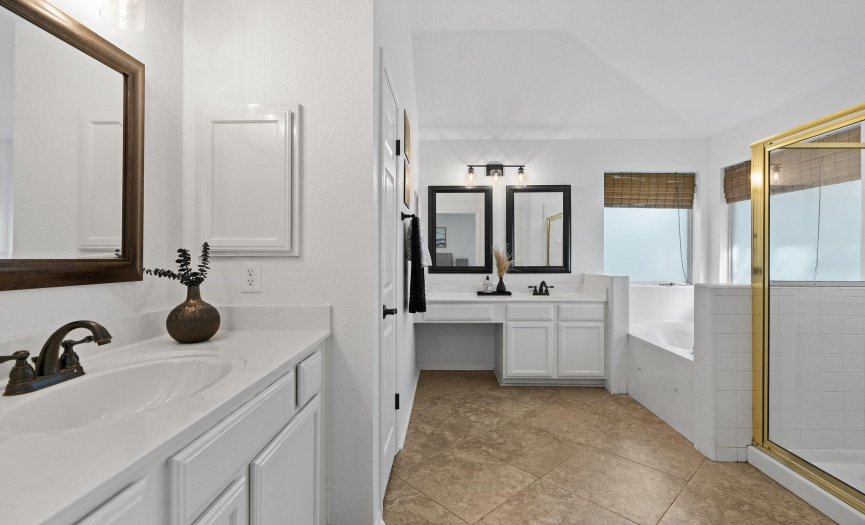 Indulge in the luxurious primary bathroom, featuring separate vanities, a soothing soaking tub, and a spacious walk-in shower for ultimate relaxation.