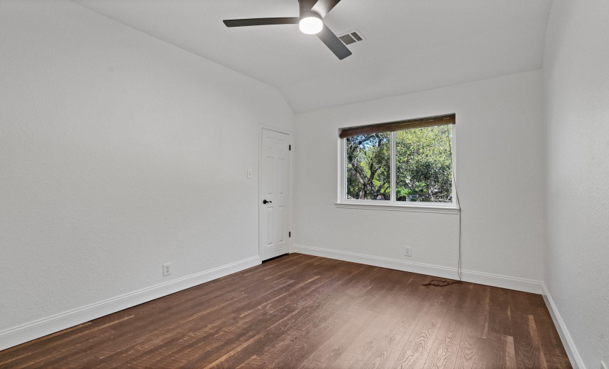 The third bedroom offers a cozy space with wood flooring and ample room for relaxation or productivity.