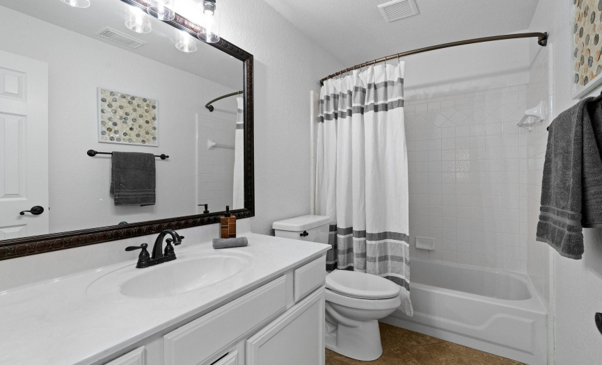 The guest bathroom offers convenience and functionality with a vanity, bathtub/shower combo, and stylish finishes for guests' comfort.