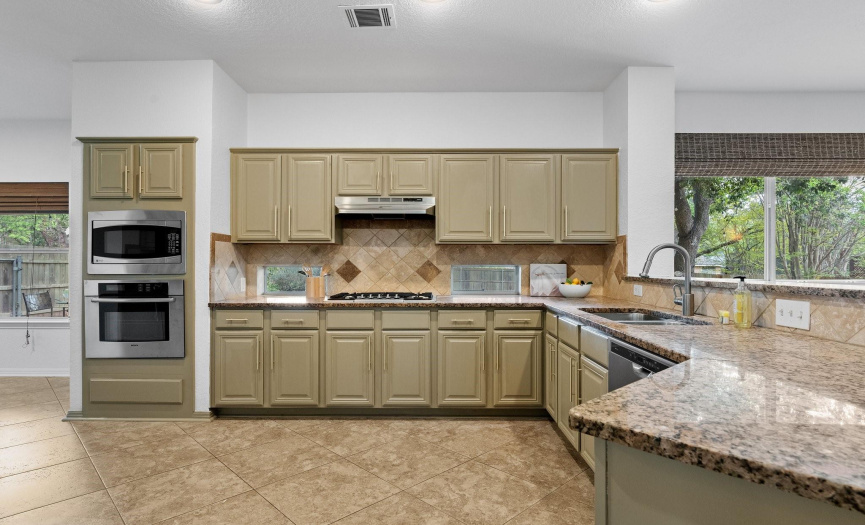 The chef's kitchen boasts ample space for cooking and entertaining, featuring granite countertops and a stylish tile backsplash.