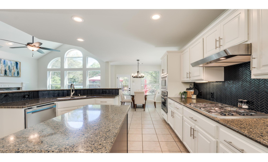 Featuring sleek granite countertops, stainless steel appliances, a center prep island, and stylish updated tile backsplash. 