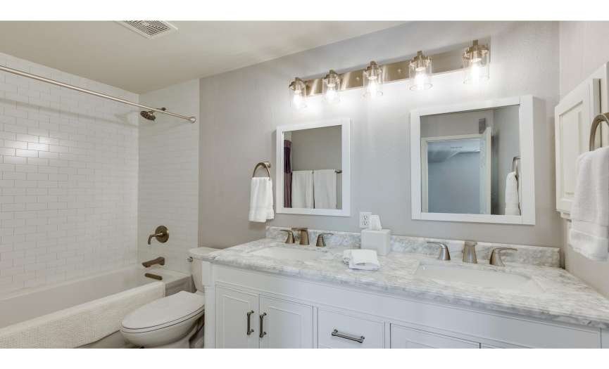 Upstairs you will also find this beautifully updated full secondary bath with a gorgeous dual vanity, elegant fixtures and hardware, and a shower/tub combo with subway tile backsplash that stretches all the way to the ceiling. 