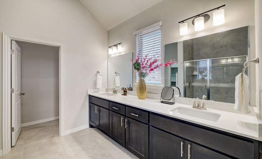 The primary bathroom features a double vanity and a window allowing for wonderful natural light to flow inside.