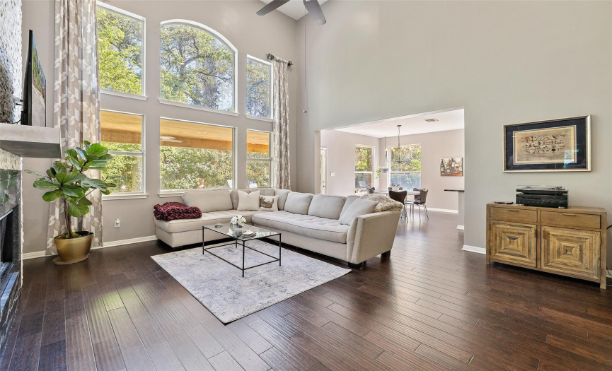 The living room is spacious with soaring high ceilings, a ceiling fan, and a tremendous amount of natural light.
