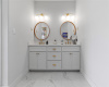 Double vanity in the primary bathroom with quartz countertop and marble tile flooring