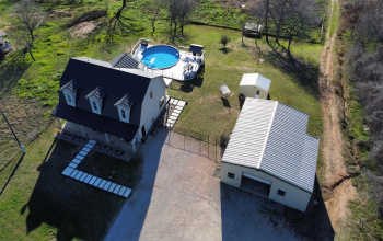 Overview of home, two shops, pool and deck as well as partial view of fenced in area for horses
