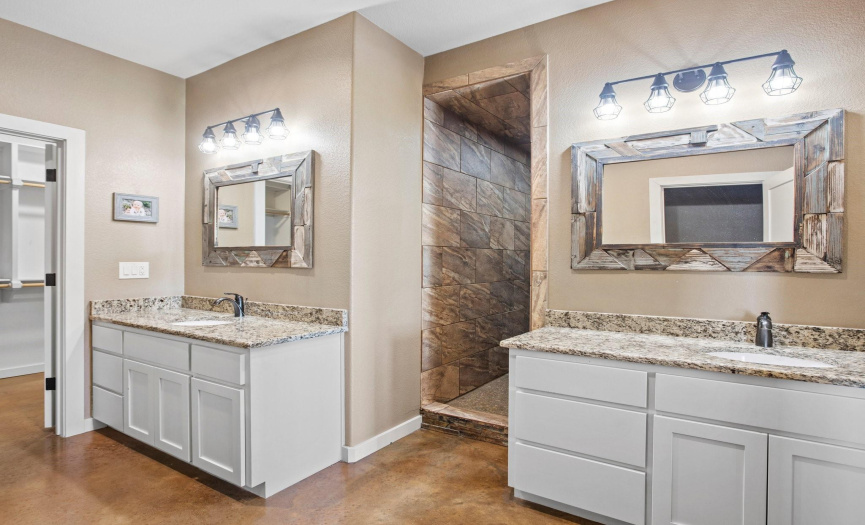 The large primary bathroom features double vanities, two closets, a safe room, and a large walk in shower. 